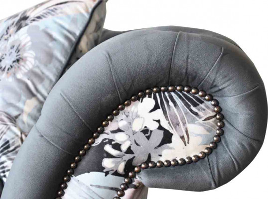 Un canapé trois places remarquable de style Chesterfield avec une délicate décoration florale grise.