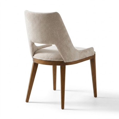 Une chaise laconique et moderne avec de hauts pieds en bois et un revêtement d'une agréable couleur crème claire pour la salle à manger.