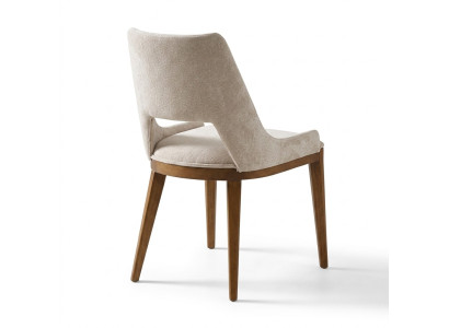 Une chaise laconique et moderne avec de hauts pieds en bois et un revêtement d'une agréable couleur crème claire pour la salle à manger.