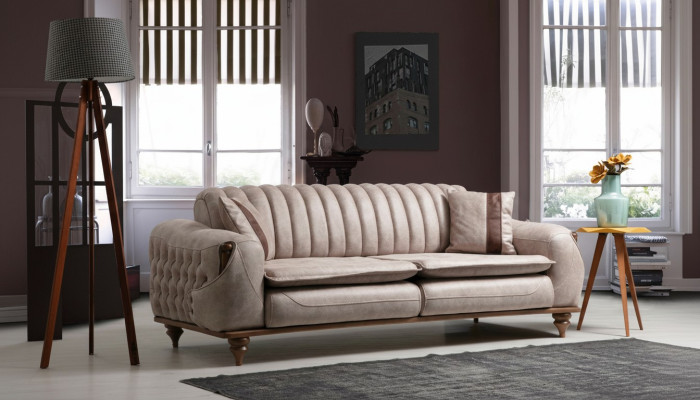 Canapé Chesterfield trois places beige en tissu d'ameublement.
